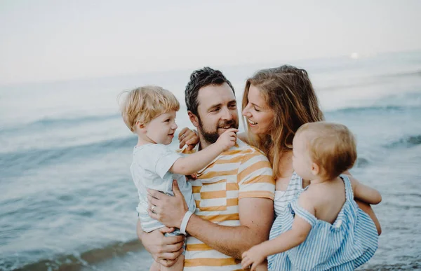 Une famille avec deux enfants en bas âge marchant sur la plage pendant les vacances d'été . — Photo