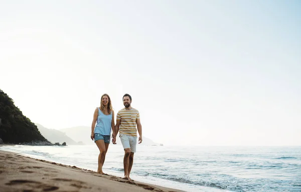Um homem e uma mulher alegres andando na praia nas férias de verão. Espaço de cópia . — Fotografia de Stock