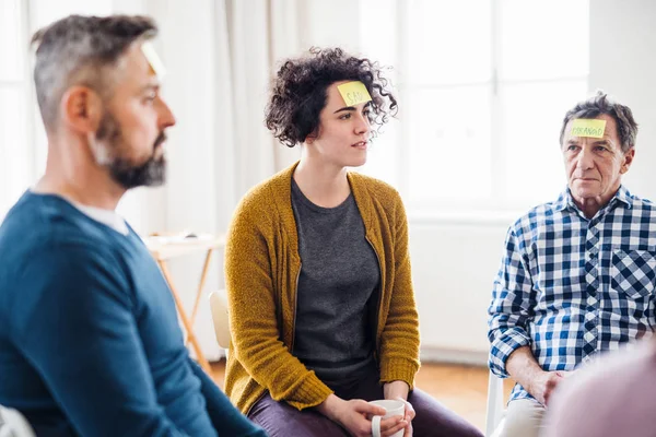 Men and women sitting in a circle during group therapy, adhesive notes on forehead. — Stock Photo, Image