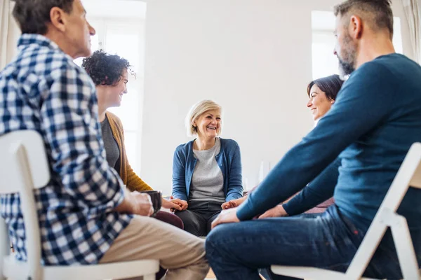 Mannen en vrouwen zitten in een cirkel en hand in hand tijdens groepstherapie. — Stockfoto