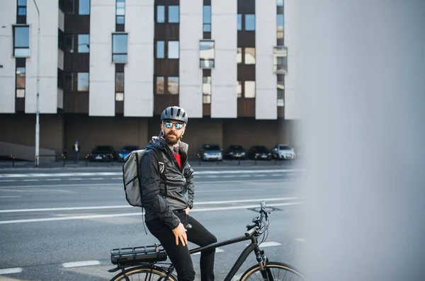 Courrier cycliste masculin avec sac à dos et lunettes de soleil livrant des colis en ville . — Photo