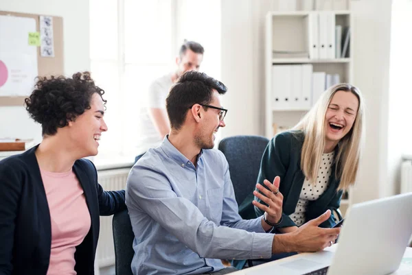 Groep van jonge ondernemers rond tafel in een modern kantoor, bijeenkomst. — Stockfoto