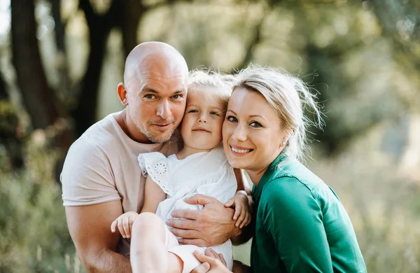 Família jovem com uma pequena filha na natureza ensolarada do verão . — Fotografia de Stock