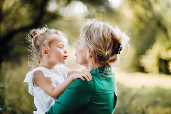 Ung mamma i naturen innehav liten dotter i armarna. — Stockfoto