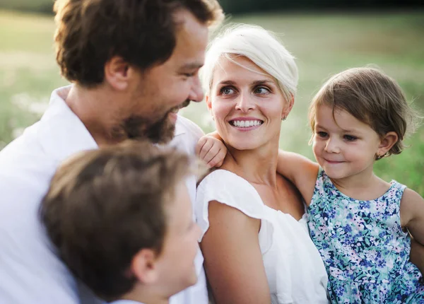 Junge Familie mit kleinen Kindern im Sommer Natur bei Sonnenuntergang. — Stockfoto