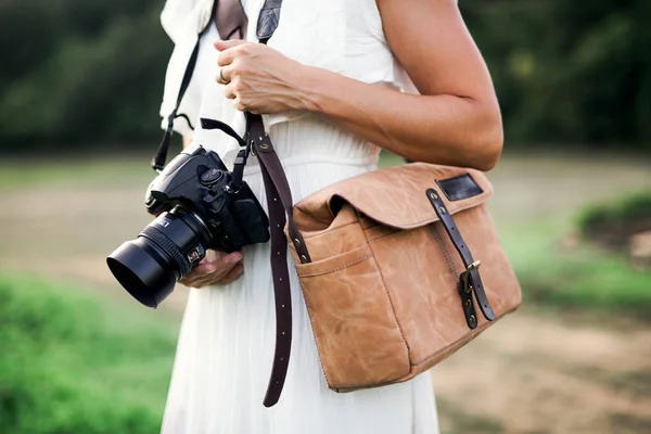 Bir midsection doğa holding bir kamera ve bir kahverengi deri çanta içinde kadın. — Stok fotoğraf