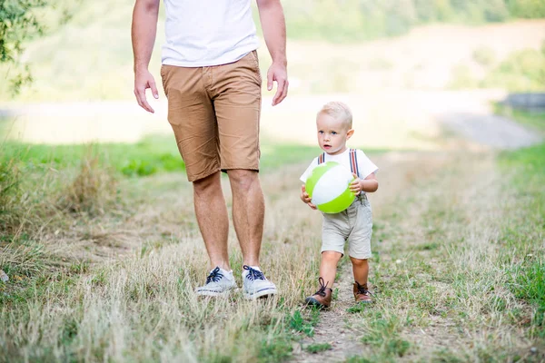 Jovem pai com um pequeno filho criança andando na natureza ensolarada verão . — Fotografia de Stock