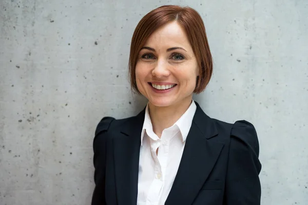 A portrait of young businesswoman standing in office, looking at camera. — Stock Photo, Image