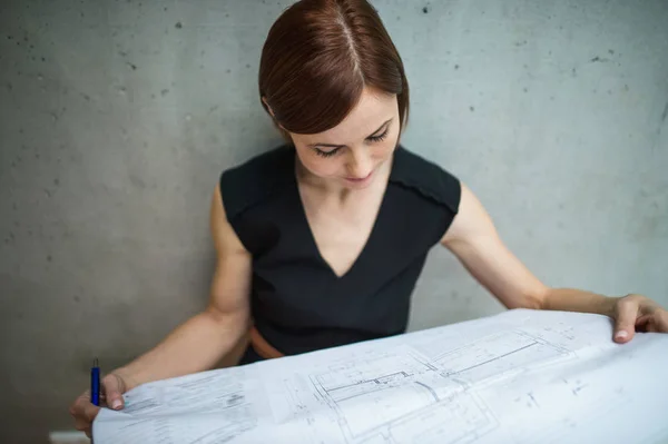 Ung affärskvinna eller arkitekt med ritningar som står i office. — Stockfoto