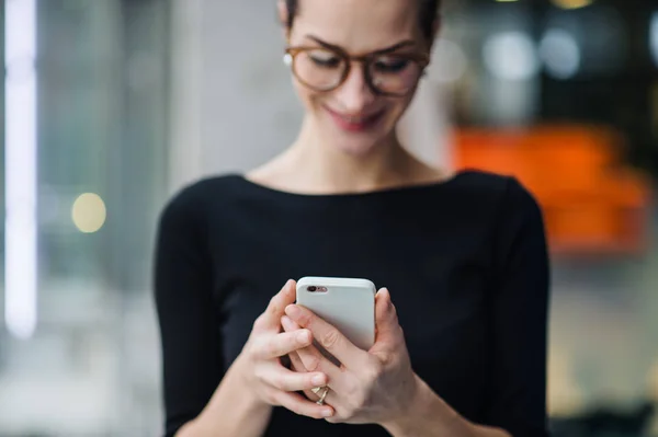 Una giovane donna d'affari con smartphone in piedi in ufficio . — Foto Stock