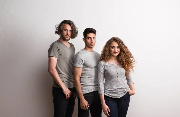 Retrato de una joven con dos amigos varones de pie en un estudio . —  Fotos de Stock