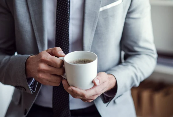 A midsection of businessman standing in an office, holding a cup of coffee. — Stock Photo, Image