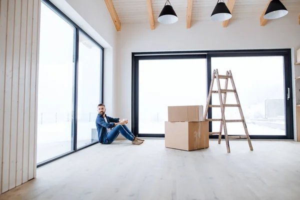 Зрілий чоловік з картонними коробками сидить на підлозі, облаштовуючи новий будинок . — стокове фото