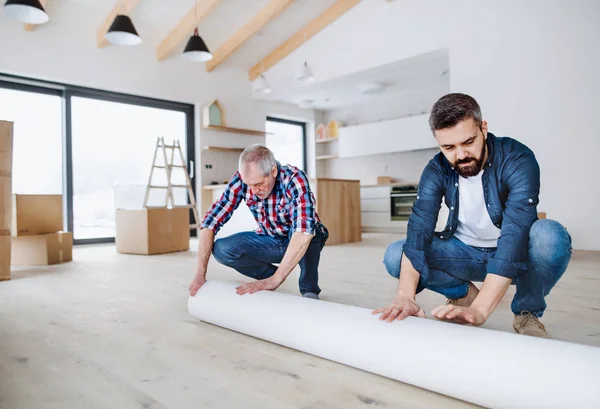 Un hombre mayor ayudando a su hijo a amueblar una casa nueva, un nuevo concepto de hogar . — Foto de Stock