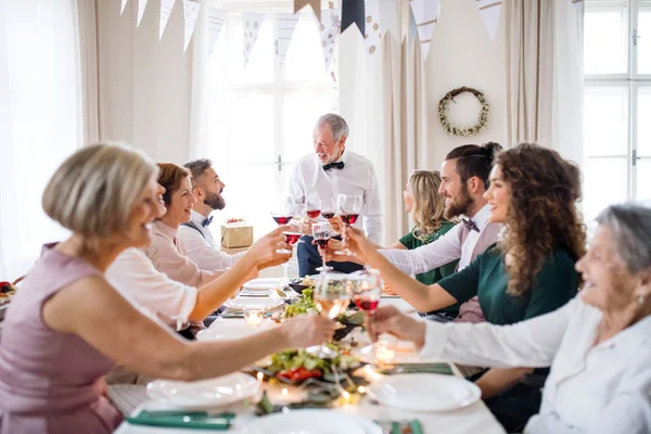 Una gran familia sentada en una mesa en una fiesta de cumpleaños cubierta, gafas de tintineo . — Foto de Stock