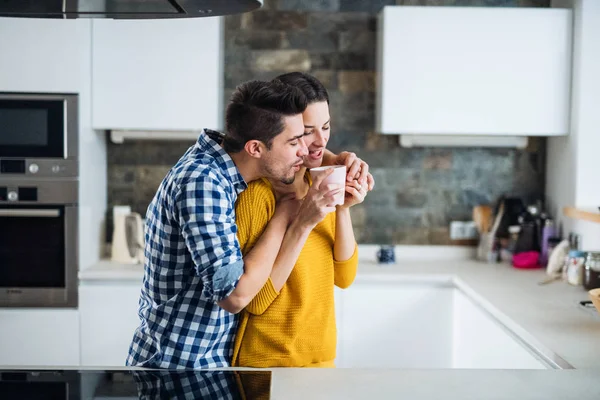 Nuori pari seisoo keittiössä kotona, juo kahvia . — kuvapankkivalokuva