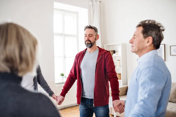 Grupp människor med slutna ögon står i en cirkel och hålla händerna under behandling. — Stockfoto