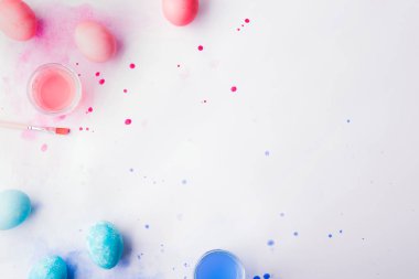 Yumurta, boya ve fırça düz beyaz bir arka plan üzerinde yatıyordu. Paskalya ve bahar kompozisyon.