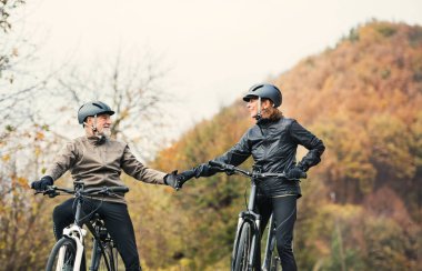 Electrobikes açık havada doğa bir yolda duran ile etkin üst düzey çift.