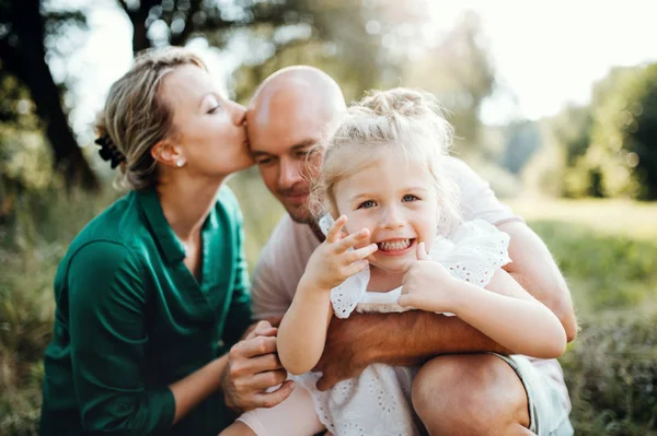 Família jovem com uma pequena filha na natureza ensolarada do verão . — Fotografia de Stock