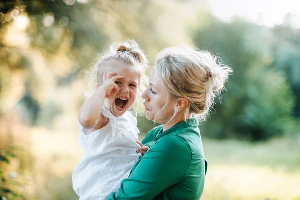 Young mother comforting crying small daughter in summer in nature. — Stock Photo, Image