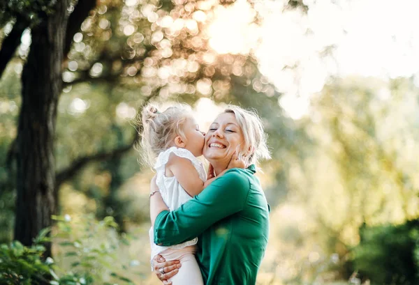 Young mother in nature with small daughter, kissing. — Stock Photo, Image