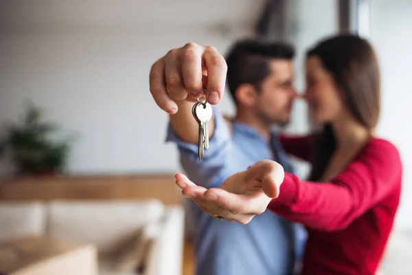 A young couple with a key and cardboard boxes moving in a new home.