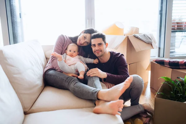 Ritratto di una giovane coppia con un bambino e scatole di cartone che si muovono in una nuova casa . — Foto Stock