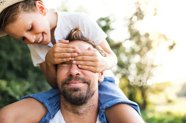 Mladý otec v přírodě dávat malého syna Svezeme se chlapec pokrývající mans oči. — Stock fotografie