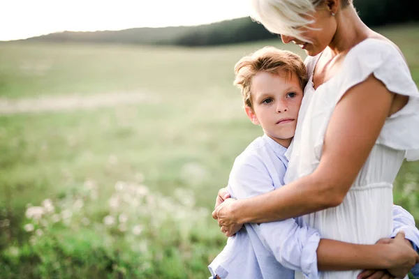En liten pojke kramar hans ung mamma utomhus i naturen. — Stockfoto