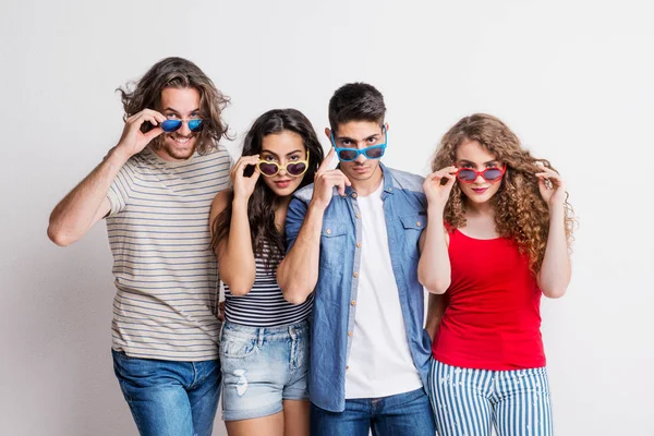 Retrato de jovem grupo alegre de amigos com óculos de sol funky em pé em um estúdio . — Fotografia de Stock