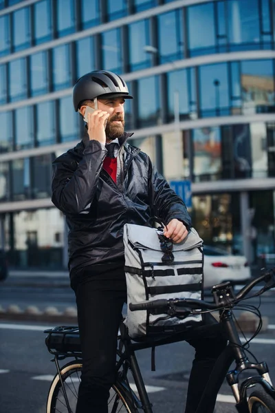 Mensajero masculino con paquetes de entrega de bicicletas en la ciudad, haciendo una llamada telefónica . — Foto de Stock