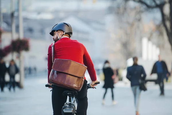 Eine Rückansicht von Geschäftsmann Pendler mit Elektro-Fahrrad auf dem Weg zur Arbeit in der Stadt. — Stockfoto