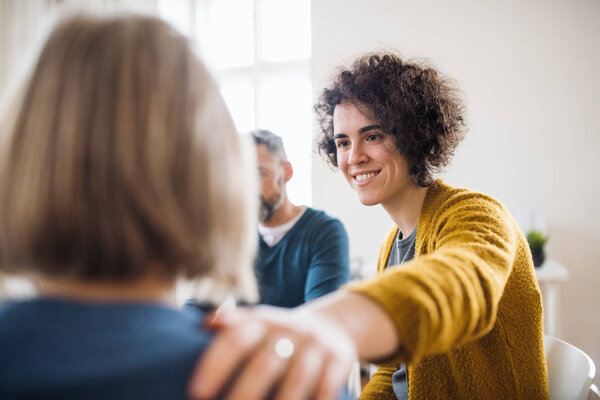 Men and women sitting in a circle during group therapy, supporting each other.