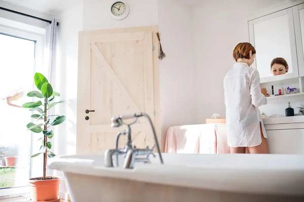 A young woman putting on a make-up in the morning in a bathroom. — Stock Photo, Image