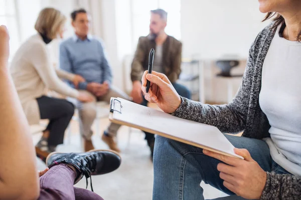 Een buik van raadgever met Klembord naar een client te praten tijdens groepstherapie. — Stockfoto