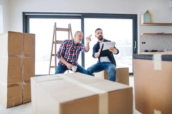 Un hombre mayor ayudando a su hijo a amueblar una casa nueva, un nuevo concepto de hogar . — Foto de Stock