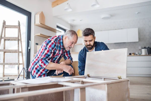 Un uomo maturo con il padre anziano che assembla mobili, un nuovo concetto di casa . — Foto Stock