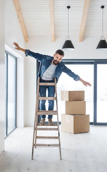 段ボール箱、はしごの上に立って、新しい家の家具と中年の男性. — ストック写真