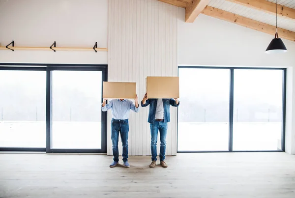 Két férfi gazdaság karton dobozok előtt a fejüket, amikor új ház berendezése. — Stock Fotó