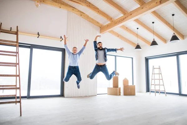 Un uomo maturo che salta con il padre anziano in una nuova casa, un nuovo concetto di casa . — Foto Stock