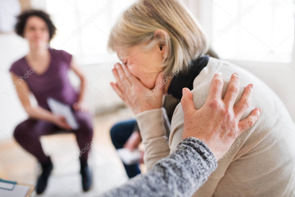 A senior depressed woman crying during group therapy.