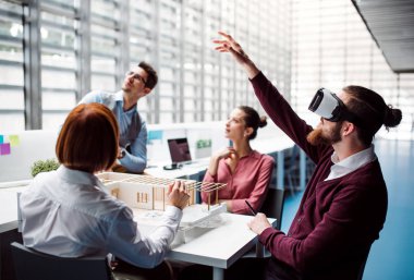 Ofiste çalışan genç Mimarlar grubu modeli Vr ve bir ev ile koruyucu gözlük.