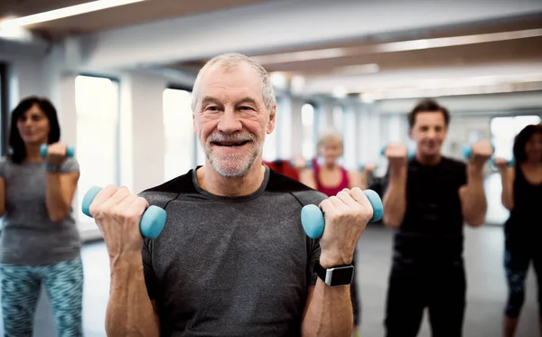 Groupe de personnes âgées gaies dans la salle de gym faire de l'exercice avec haltères . — Photo