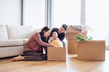Bir bebek ve karton kutular içinde yeni bir ev taşıma ile genç çift portresi.