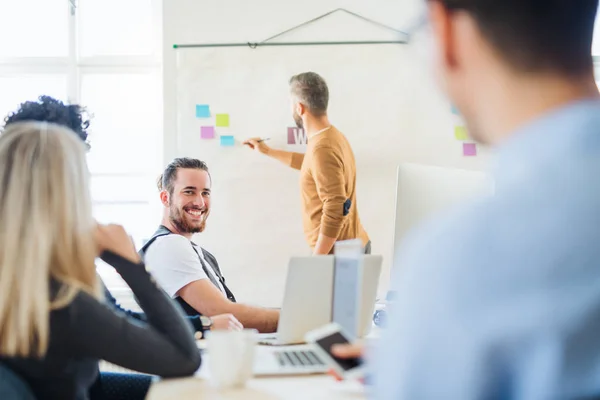 Un homme d'affaires faisant une présentation à ses collègues dans un bureau moderne . — Photo