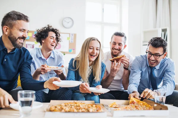 Grupo de jovens empresários com pizza almoçando em um escritório moderno . — Fotografia de Stock