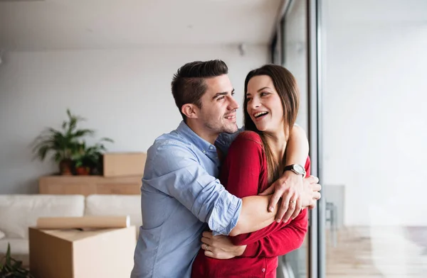 Jeune couple amoureux debout près de la fenêtre à la maison, étreignant . — Photo