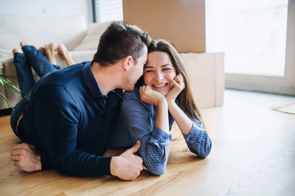 Ett ungt par med en cup och kartong lådor som rör sig i ett nytt hem. — Stockfoto