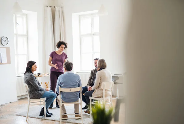 Young woman standing and talking to other people during group therapy. — Stock Photo, Image